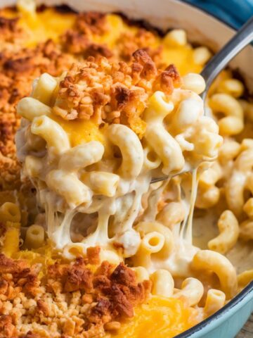 Tini's Mac and Cheese Recipe featuring creamy, cheesy macaroni with a golden, crispy breadcrumb topping, served in a light blue casserole dish. A rich and comforting homemade baked mac and cheese perfect for any occasion.