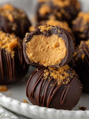 Butterfinger Balls with chocolate drizzle and crushed candy on a plate.