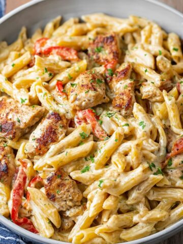 Creamy Cajun chicken pasta with penne, bell peppers, and parsley served in a bowl.