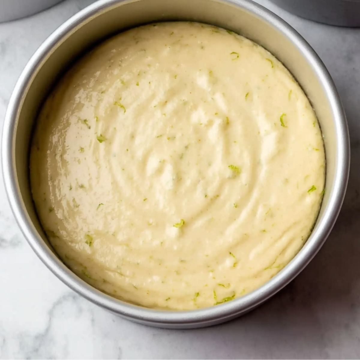 Key lime cake batter spread evenly in round cake pans.