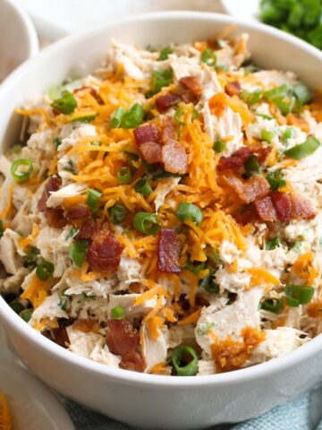 A close-up of the prepared Bacon Ranch Chicken Salad with shredded chicken, cheddar cheese, crispy bacon, and green onions.