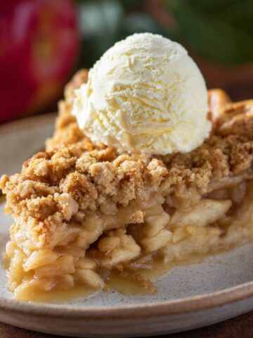 A slice of Dutch apple pie with a scoop of vanilla ice cream on top