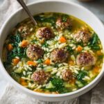 A comforting bowl of Italian Wedding Soup, featuring tender meatballs, spinach, carrots, and orzo, all simmered together in a rich broth.