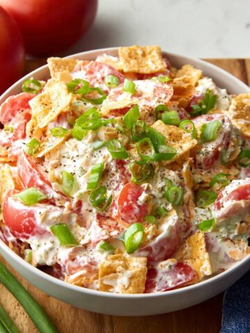 Creamy Tomato Cracker Salad with eggs, green onions, and crushed crackers, garnished with black pepper.