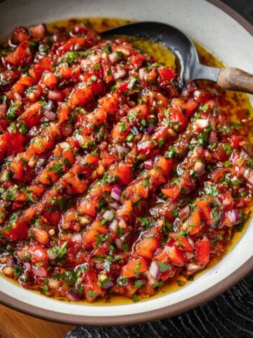 A vibrant bowl of Turkish Ezme salad with tomatoes, onions, and herbs in a rich dressing.