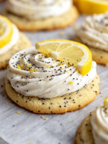 A batch of soft and fluffy Lemon Poppy Seed Cheesecake Cookies topped with lemon slices and poppy seeds.