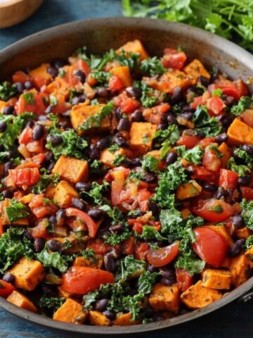 A colorful Sweet Potato Black Bean Skillet, black beans, tomatoes, and kale, creating a flavorful and hearty vegetable dish.